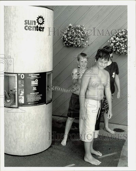 1988 Press Photo Boys spraying sunscreen at the Sun Center - lra32170- Historic Images