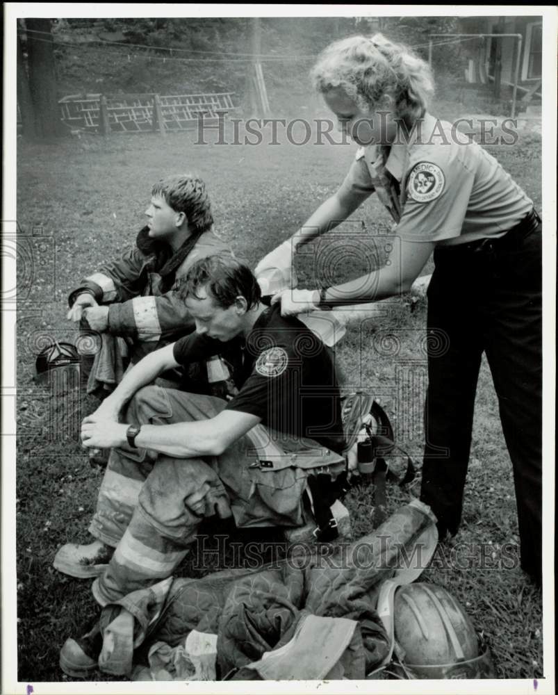 1991 Press Photo Medic Mary Hunt pours water on firefighters after fire- Historic Images