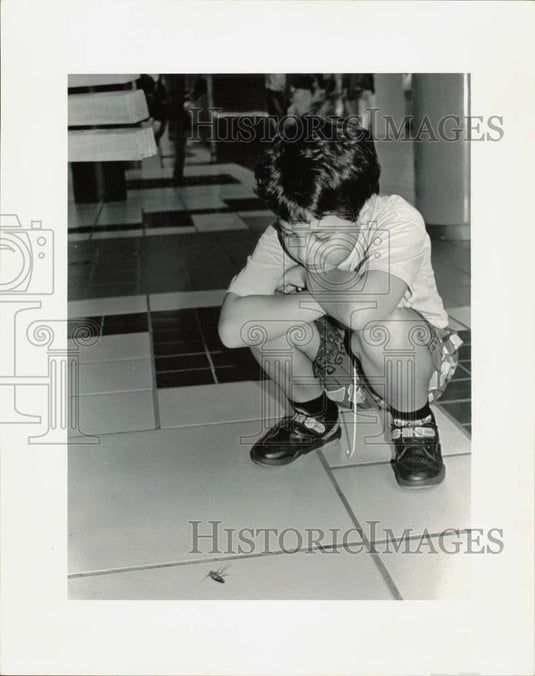 1992 Press Photo Esteban Orozco examines roach on floor of mall in Florida- Historic Images