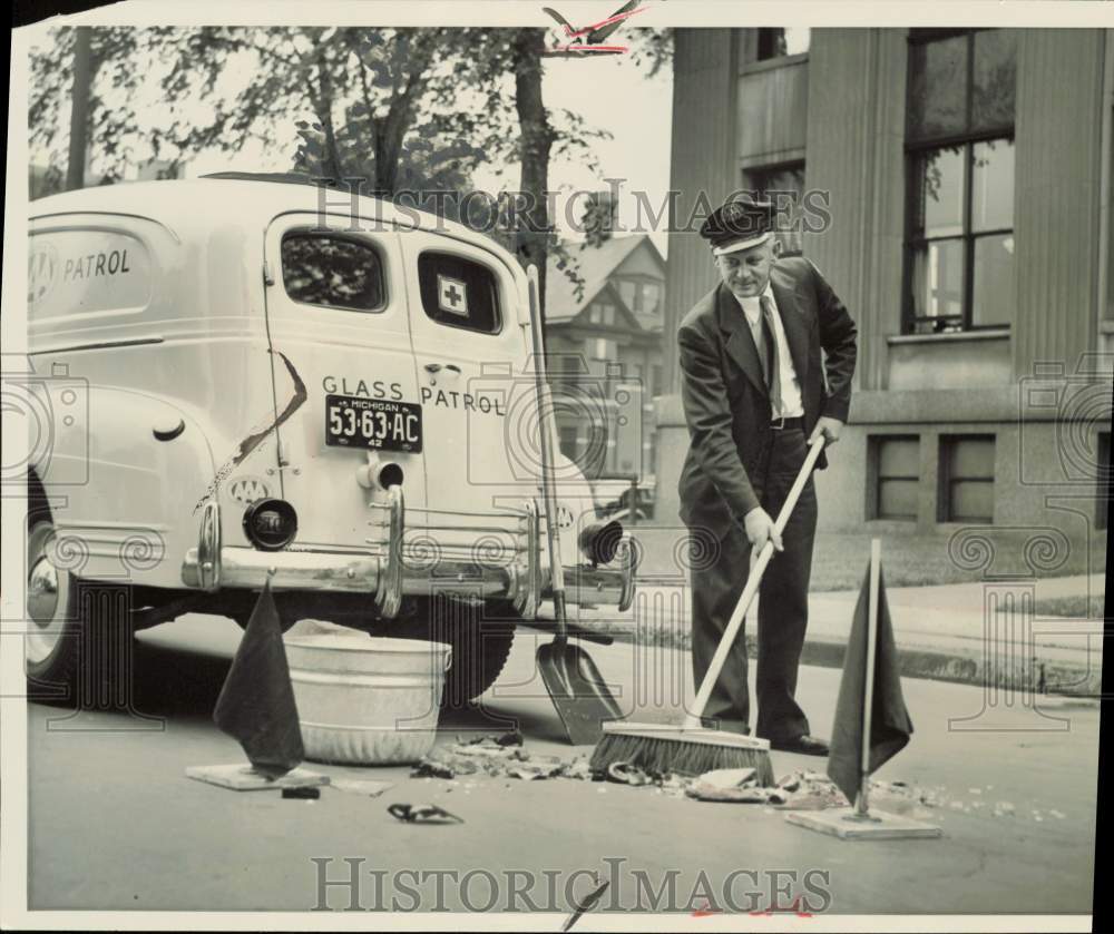 1942 Press Photo Driver Jack Liss of Auto Club of Michigan sweeps broken glass- Historic Images