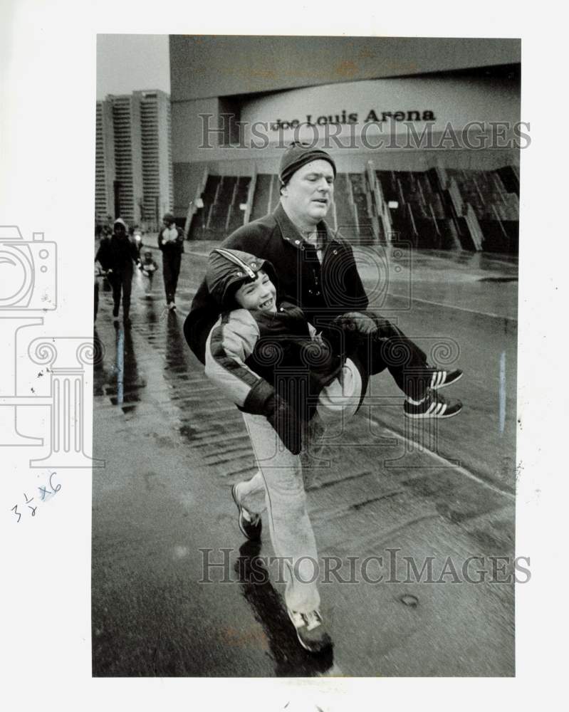 1985 Press Photo Father carries his son in New Year&#39;s Eve Family Run in Detroit- Historic Images