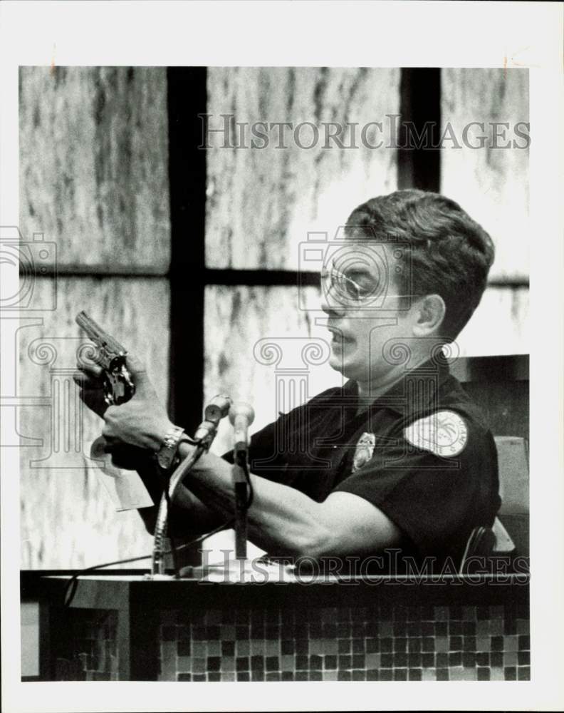 1984 Press Photo Miami policeman John Campbell demonstrates gun during hearing- Historic Images