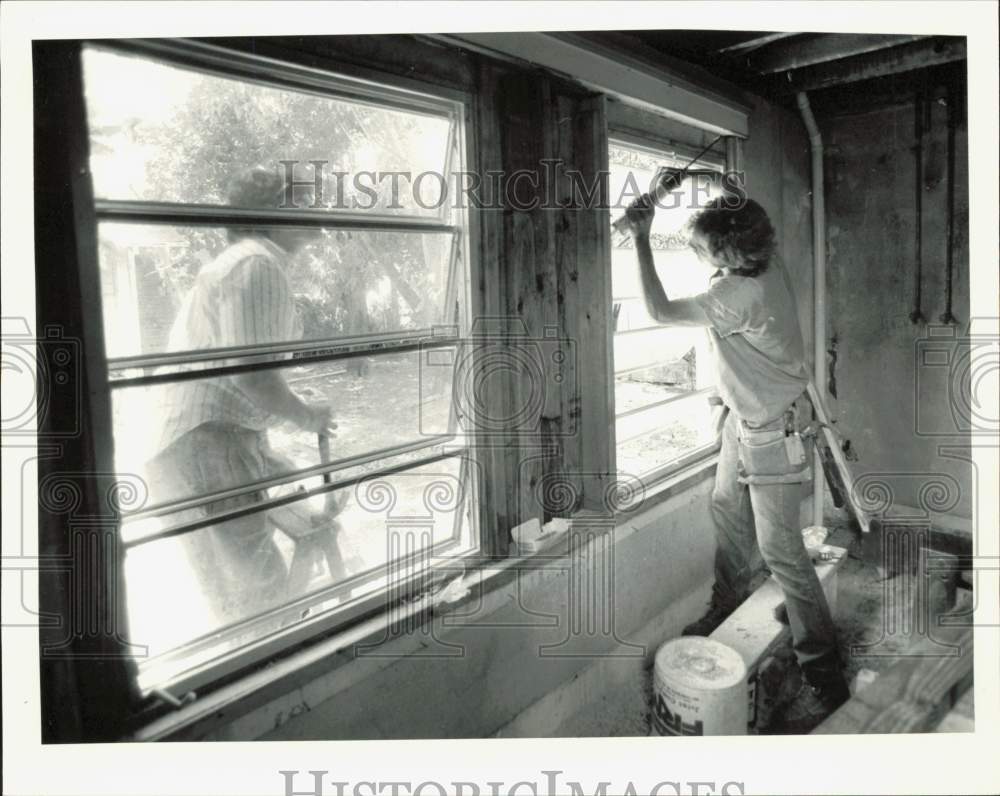 1988 Press Photo Phil Reyes and Allan Clark caulk new window in the Perez house- Historic Images