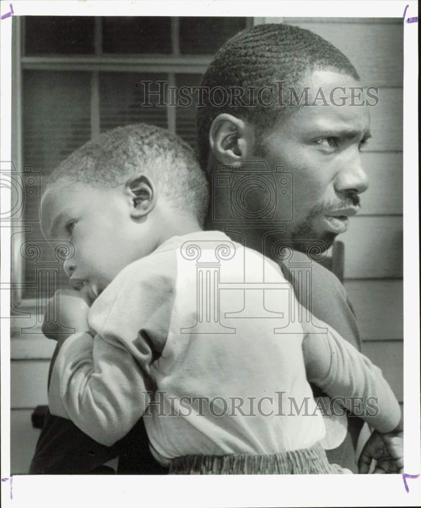 1990 Press Photo Pate Payne, holding young child discusses shooting in Charlotte- Historic Images