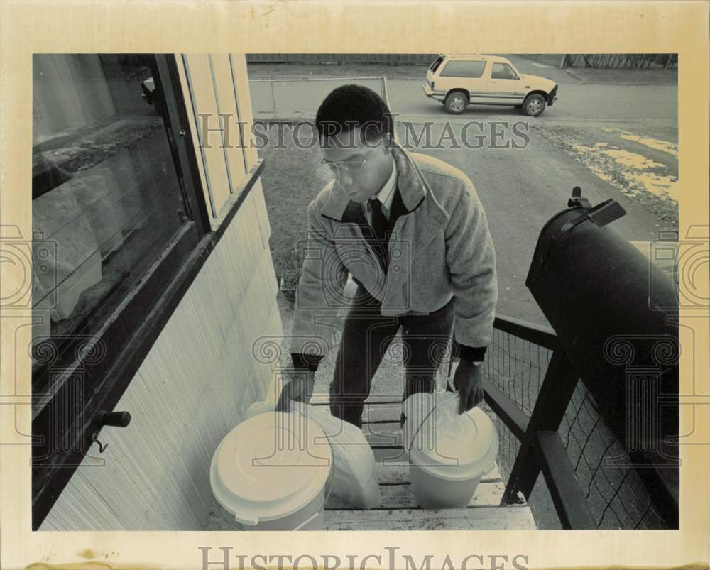 1990 Press Photo Kerry Siah carrying pails inside home in Anchorage, Alaska- Historic Images