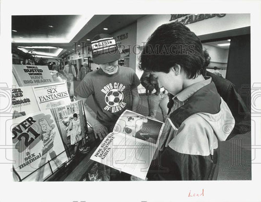 1985 Press Photo Jon Wilson & Bruce Anthony look at books in Mall, Alaska- Historic Images