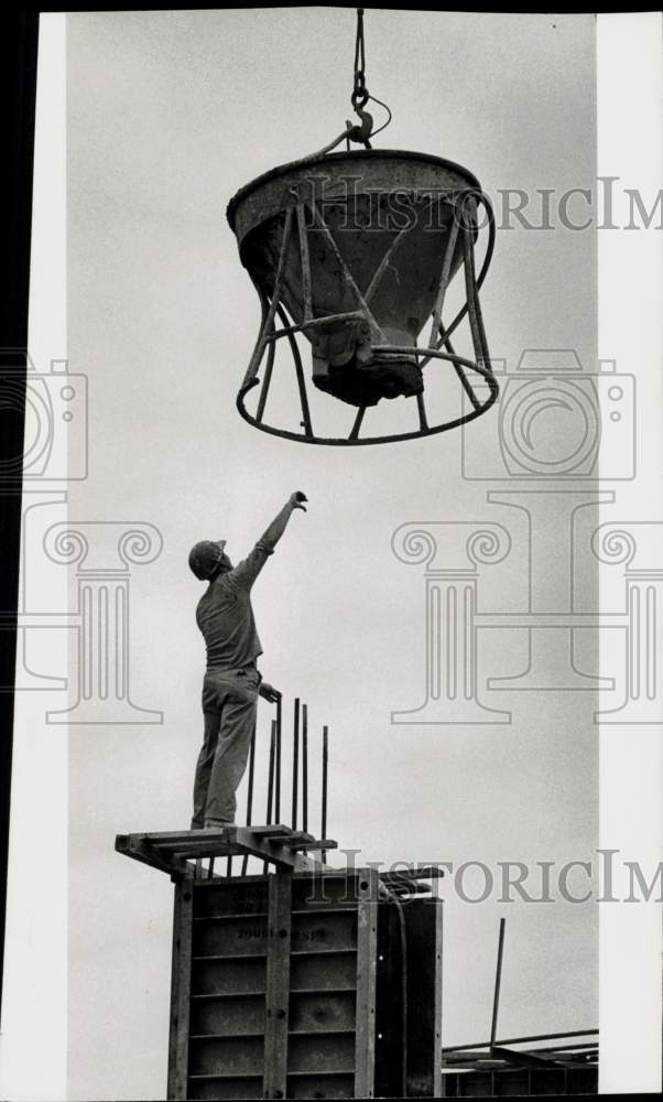 1971 Press Photo Worker directs concrete bucket during construction of stadium- Historic Images