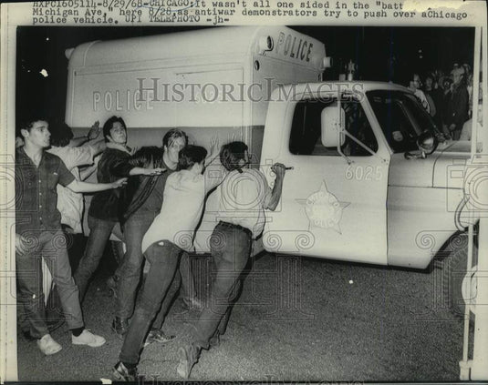 1968 Press Photo Anti-war demonstrators try to push over Chicago Police vehicle- Historic Images
