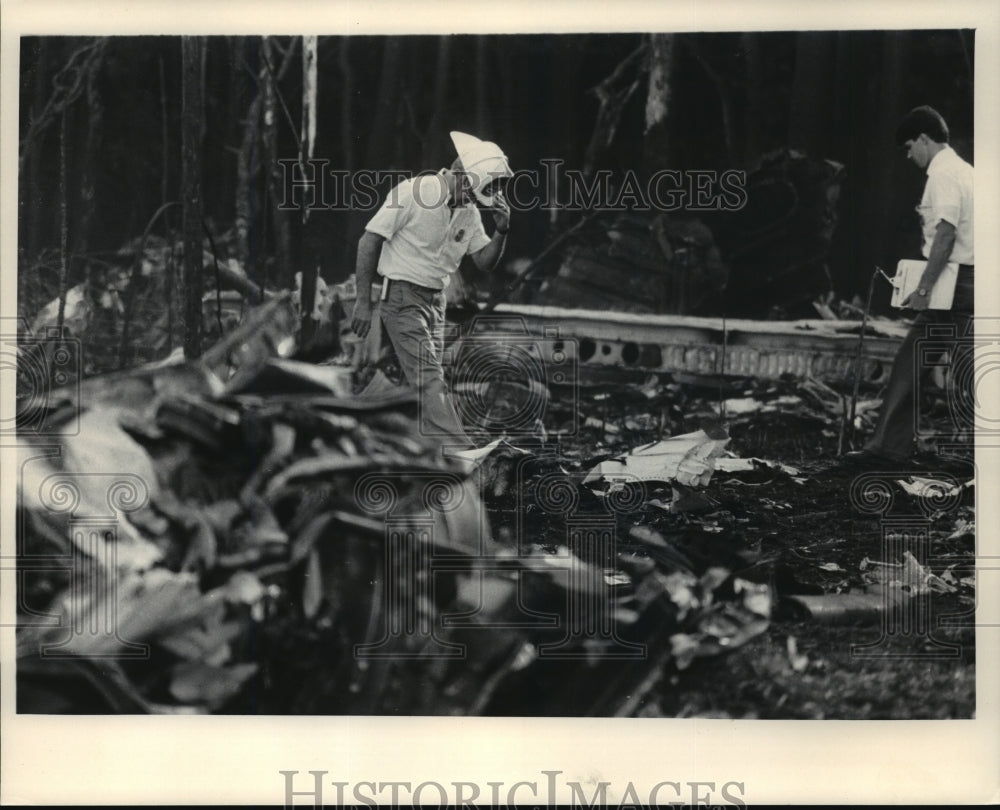 1985 Press Photo Fire Dept battalion chief through debris at airliner crash site- Historic Images