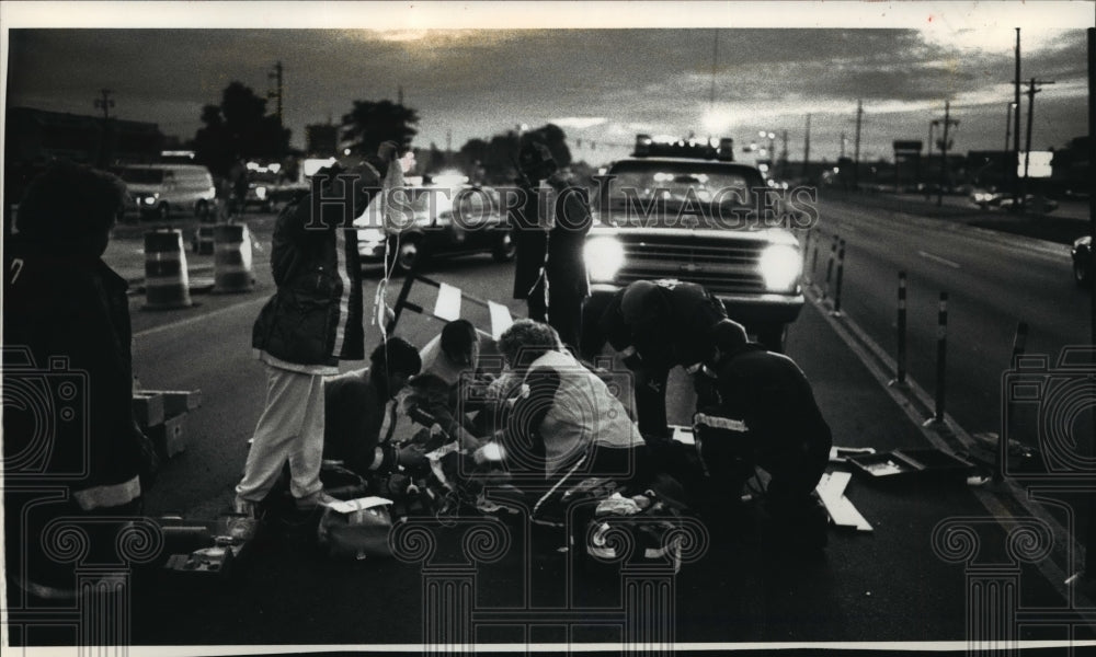 1991 Press Photo Rescue workers aid a construction worker struck by car - Historic Images