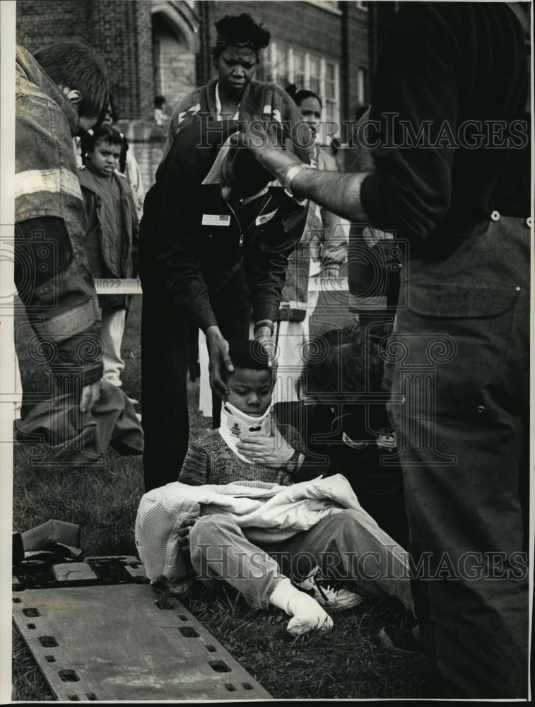 1991 Press Photo Rescue workers assist a child injured when two buses collided- Historic Images