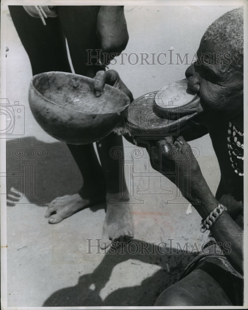 1956 Press Photo Toothless woman drinks water by pouring liquid onto lower lip- Historic Images