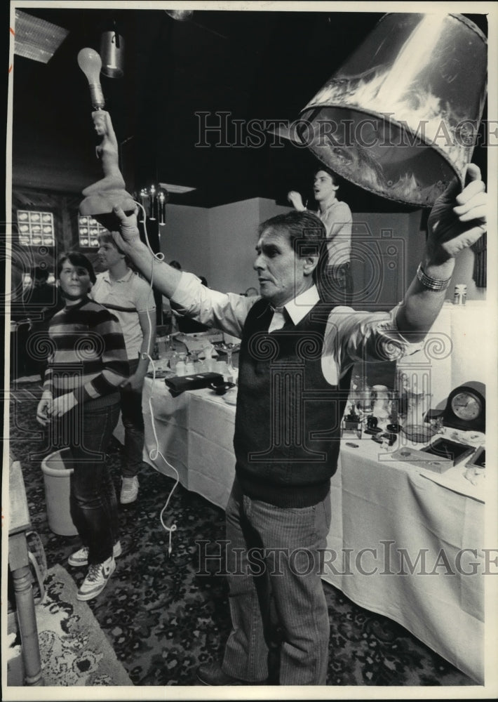 Load image into Gallery viewer, 1984 Press Photo Auctioneer Jim Adams holds up a somewhat unusual lamp and shade
