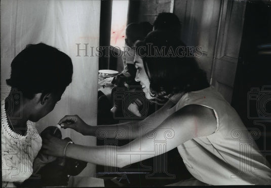 1966 Press Photo Mary Ann Comparin administering oral vaccine to a ghetto infant