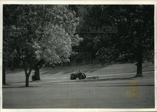 1991 Press Photo County worker Clarence Lawrence cuts the grass in Naga-Waukee- Historic Images