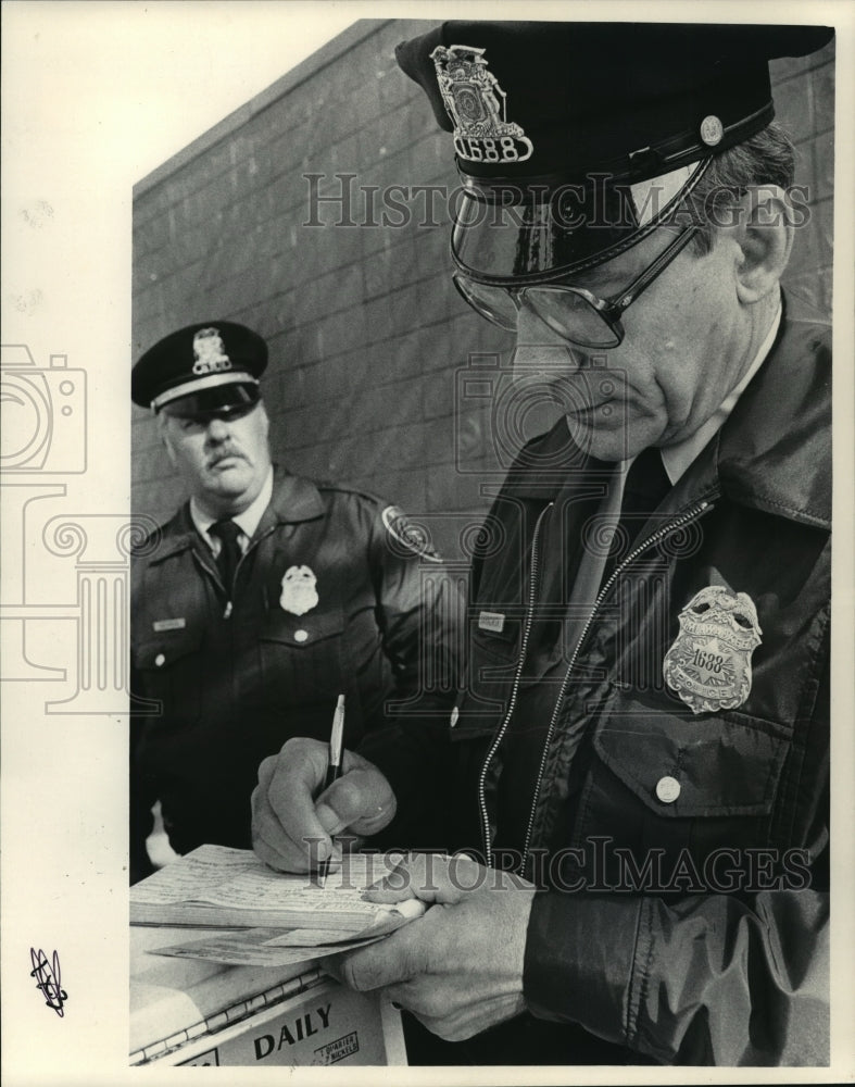 1986 Press Photo Gordon Gehrig watches as Raymond Sarnowski writes a citation- Historic Images