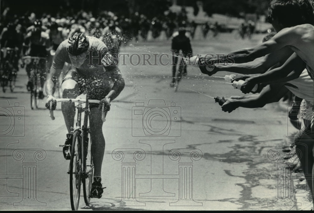 1984 Press Photo Cool water being sprayed on cyclists during Bastille Days races- Historic Images