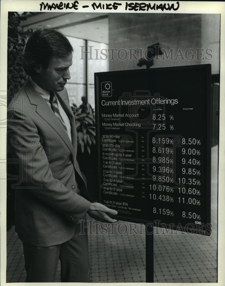 Load image into Gallery viewer, 1983 Press Photo Michael Isermann, vice president Marine Bank shows rate board
