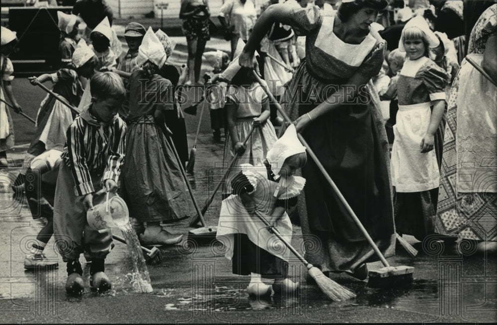 1987 Press Photo Dutch Clothed people scrub street for the Kiompen Danvers - Historic Images