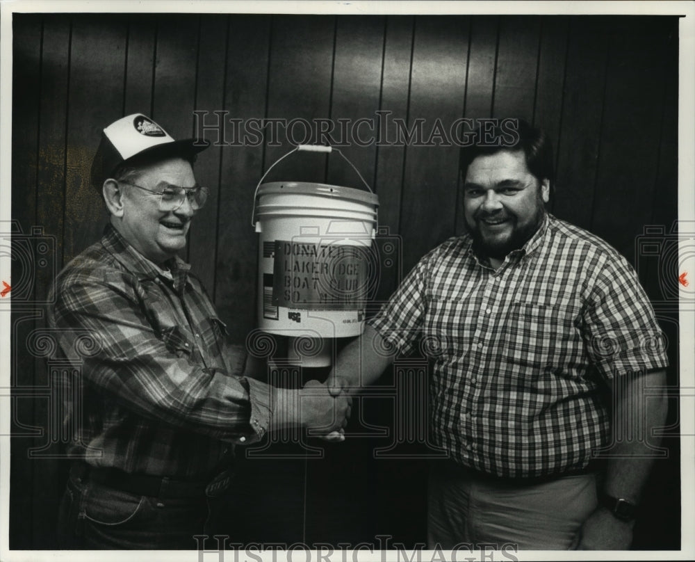 1991 Press Photo Art Strom gives fish feeder to Wis., DNR official Al Kaas. - Historic Images