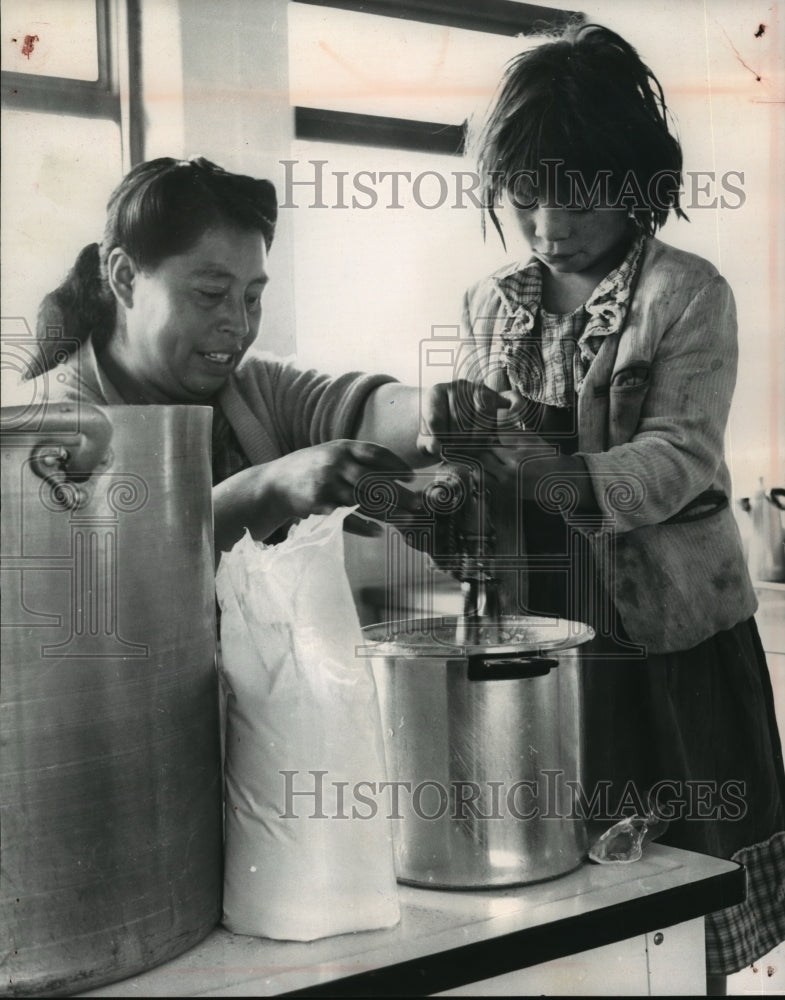 1964 Press Photo A child helping with the reconstitution of milk with water. - Historic Images