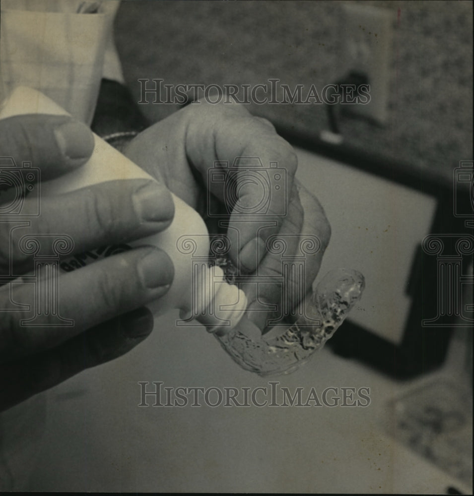 1989 Press Photo Patient putting bleach in a cup to be held in place by teeth- Historic Images