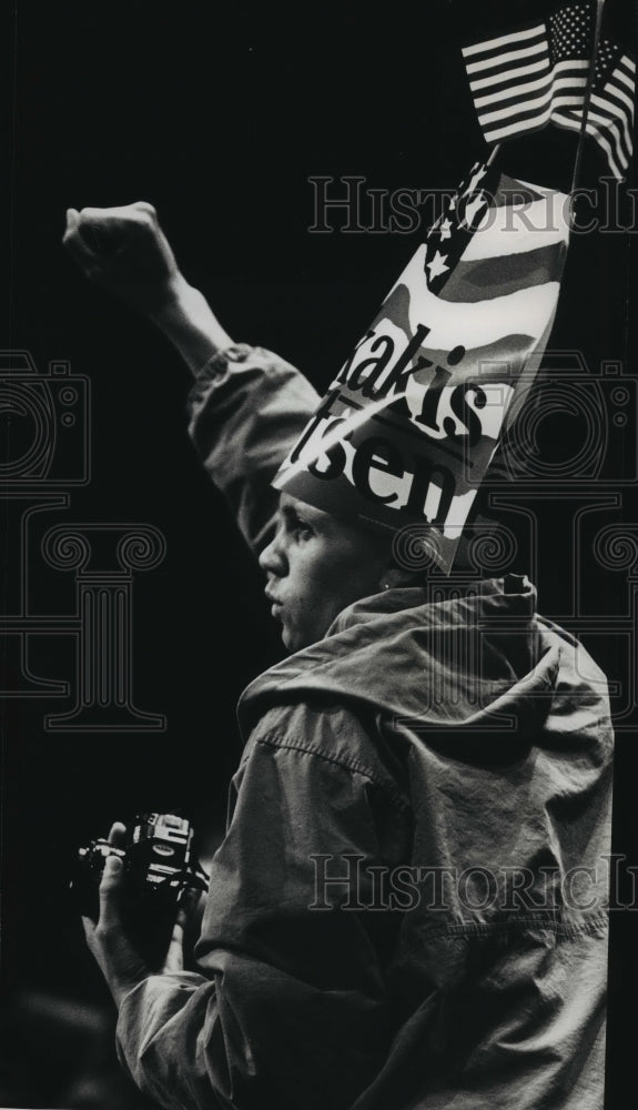 1988 Press Photo Supporter of presidential candidate Dukakis wears campaign sign- Historic Images