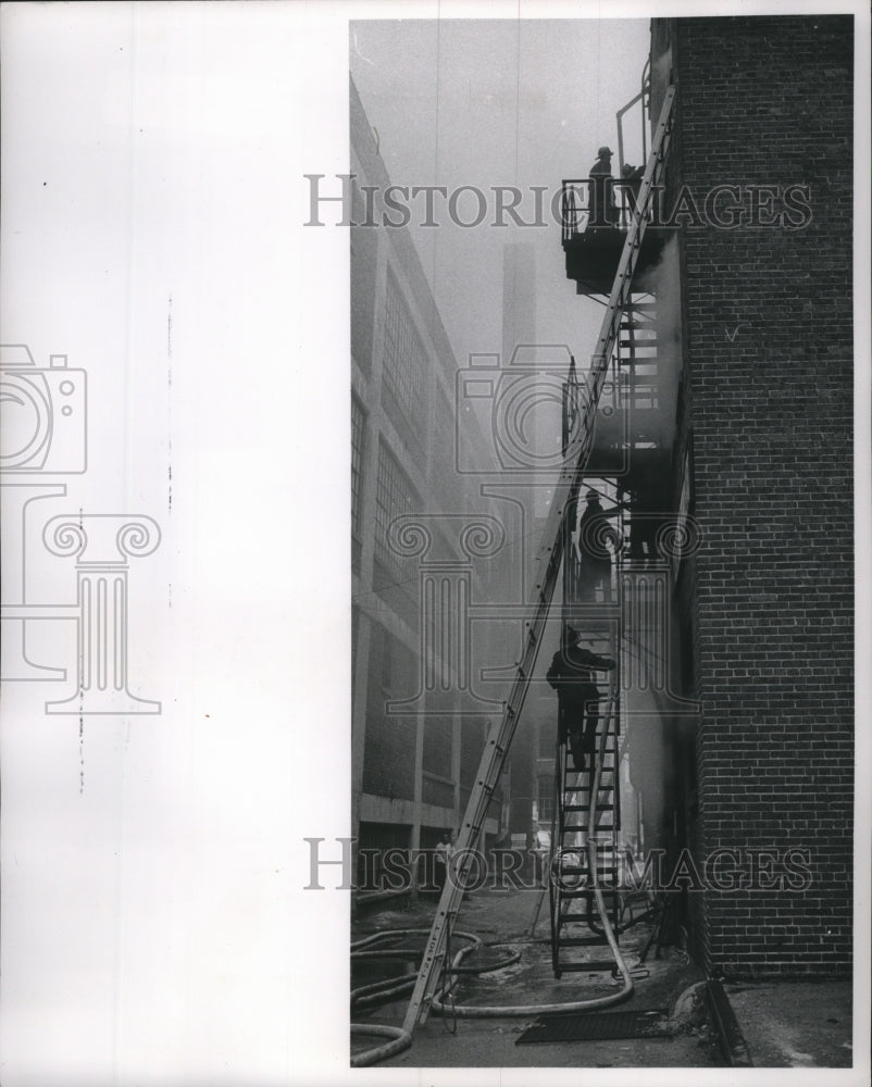 1961 Press Photo Firemen struggle up a fire escape holding a hose, Milwaukee.- Historic Images