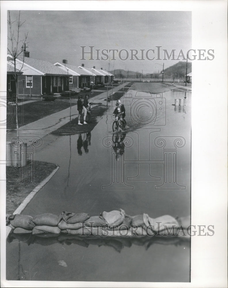 1965 Press Photo Barbara Burch rides her bicycle through Wisconsin floodwaters- Historic Images