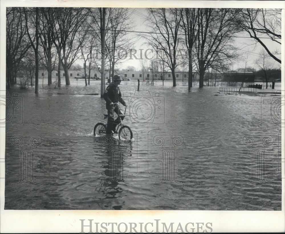 1976 Press Photo A bicyclist rides along flooded Water Street in New London