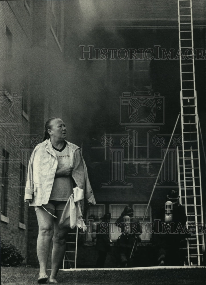 1986 Press Photo Woman walks near Building on Fire at Apartments in Milwaukee- Historic Images