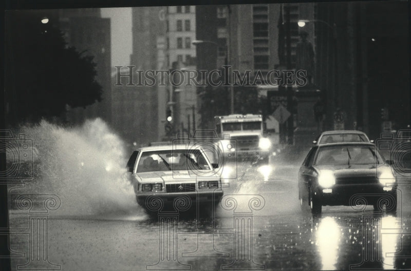 Load image into Gallery viewer, 1986 Press Photo Cars splashed on West Wisconsin Avenue during heavy rains.
