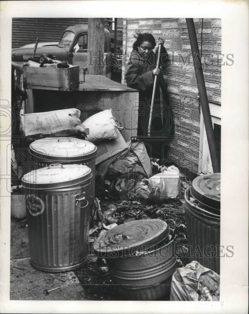 1966 Press Photo Mrs. Thaddeus Brewster, cleaning debris behind cans, Milwaukee.- Historic Images