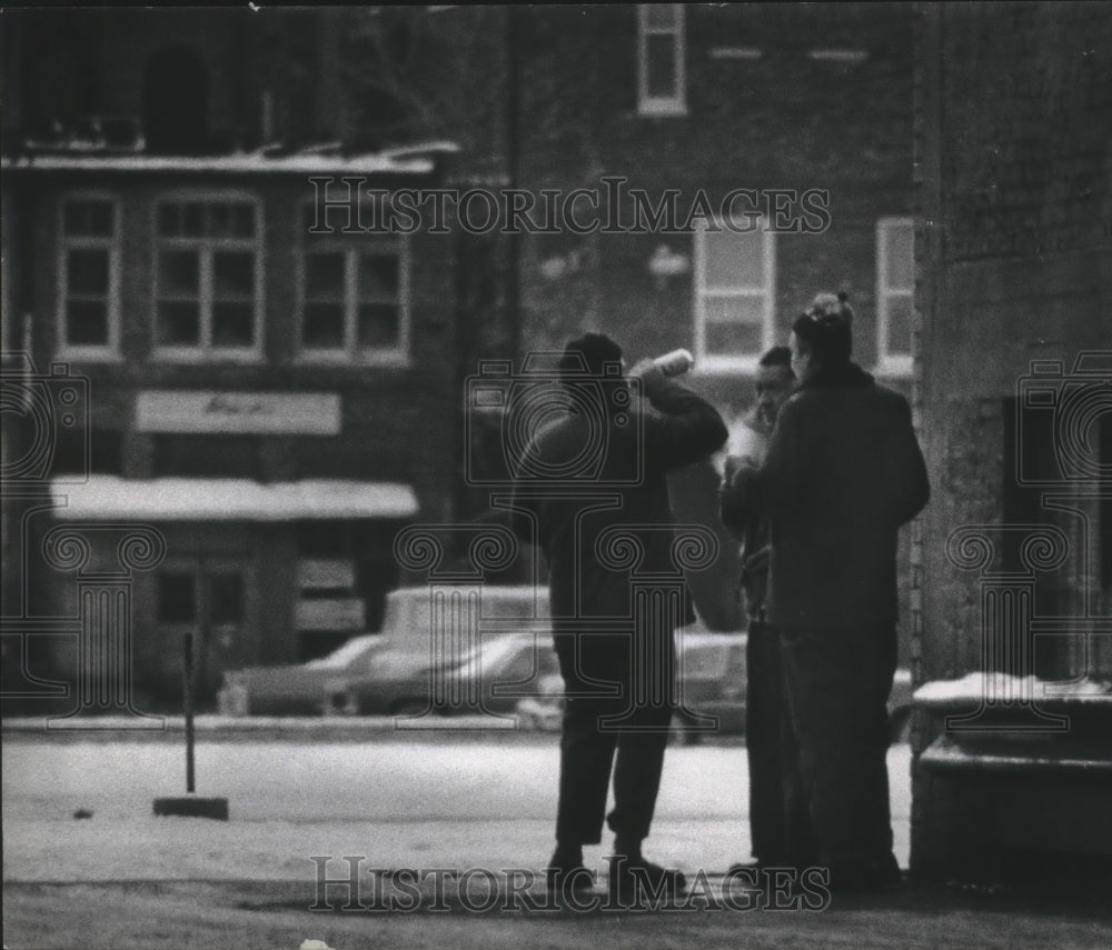 1975 Press Photo Three men on snow packed street corner smoking and drinking, WI