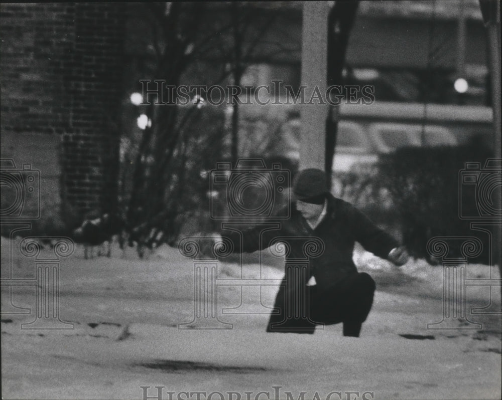 1975 Press Photo A man leaning against a utility pole on snow packed street, WI