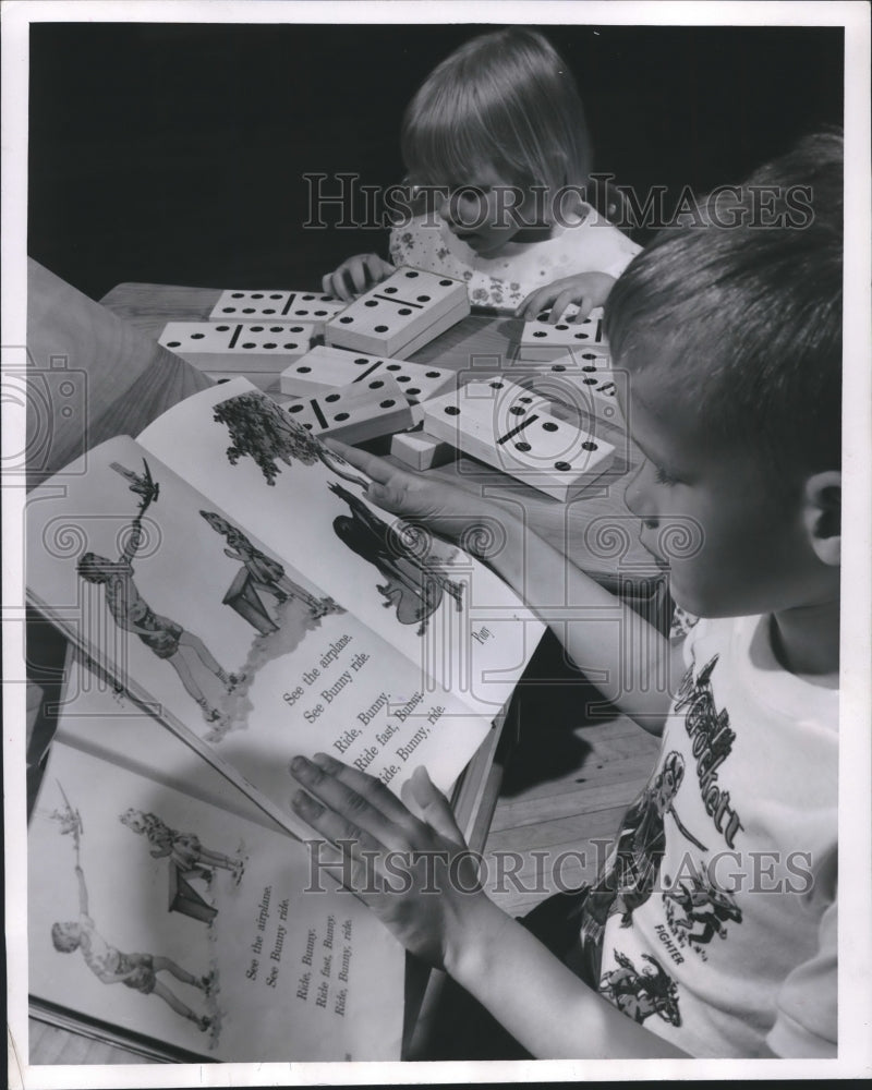 Load image into Gallery viewer, 1955 Press Photo Karen Ihda plays with domino as Donald Mowcker reads, Milwaukee

