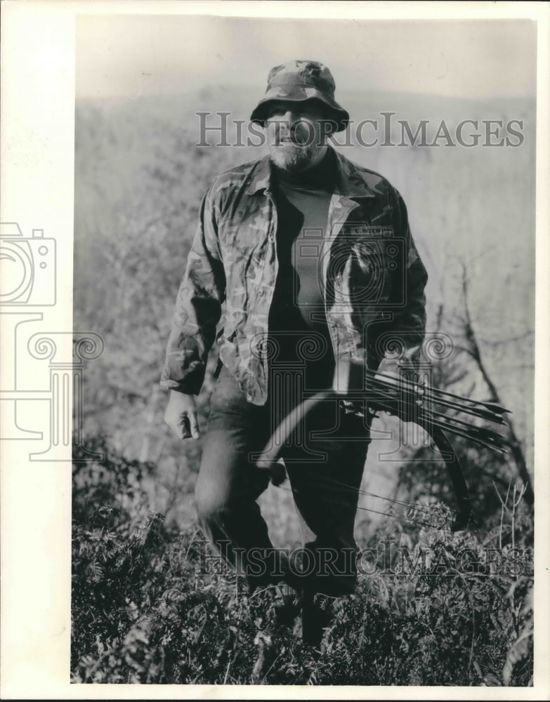 1987 Press Photo Eugene Hasenfus walks through a field to bow hunt for deer- Historic Images