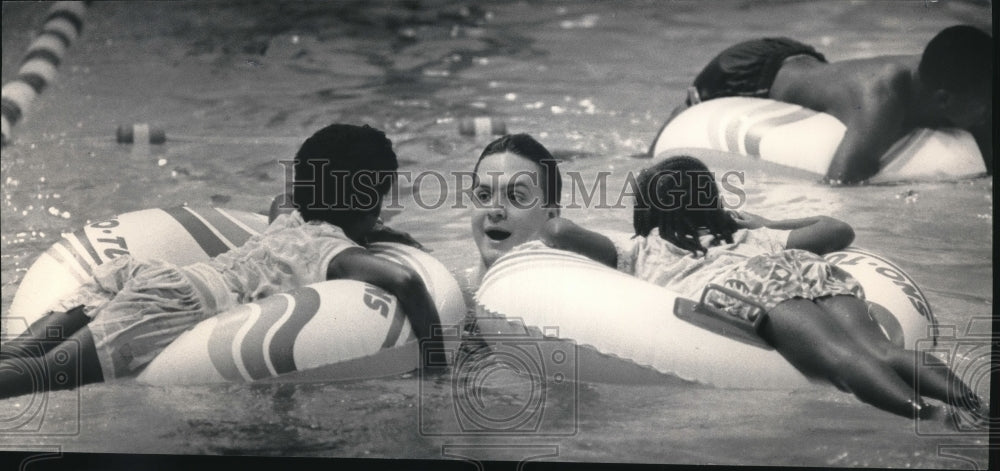 1988 Press Photo Mike Mellock helps kids ride tubes at Moody Indoor Pool- Historic Images