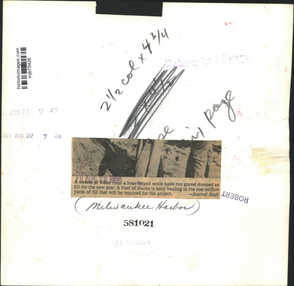 1958 Press Photo Worker sprays water on gravel fill dumped at Milwaukee Harbor