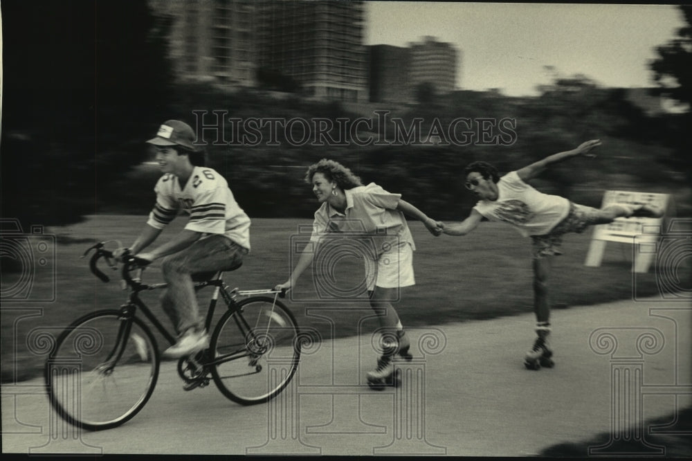 1987 Press Photo Roller skaters and bike rider in Milton using rented wheels- Historic Images