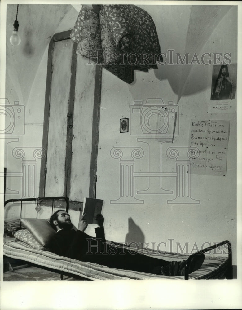 1961 Press Photo Father Timotheos reading in living quarters on mattress, Cyrus.- Historic Images