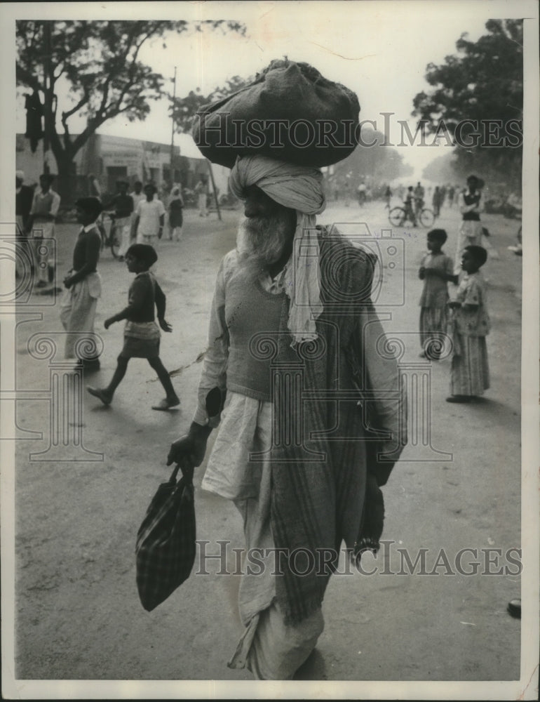 1960 Press Photo Man in Dew Delhi balances a bundle on his turban while walking- Historic Images