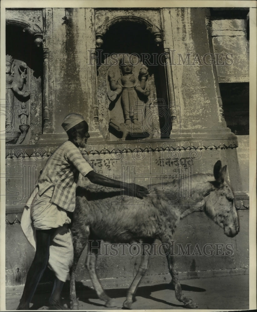 1952 Press Photo Man guides donkey past ancient Hindu statues India - mjb84337- Historic Images