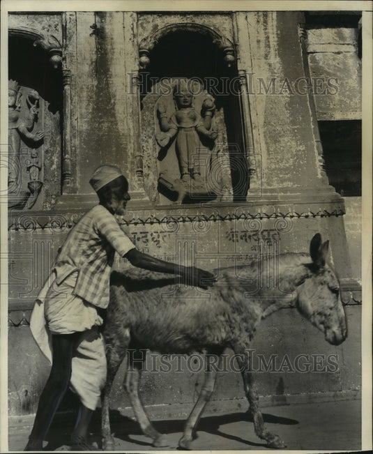1952 Press Photo Man guides donkey past ancient Hindu statues India - mjb84337- Historic Images