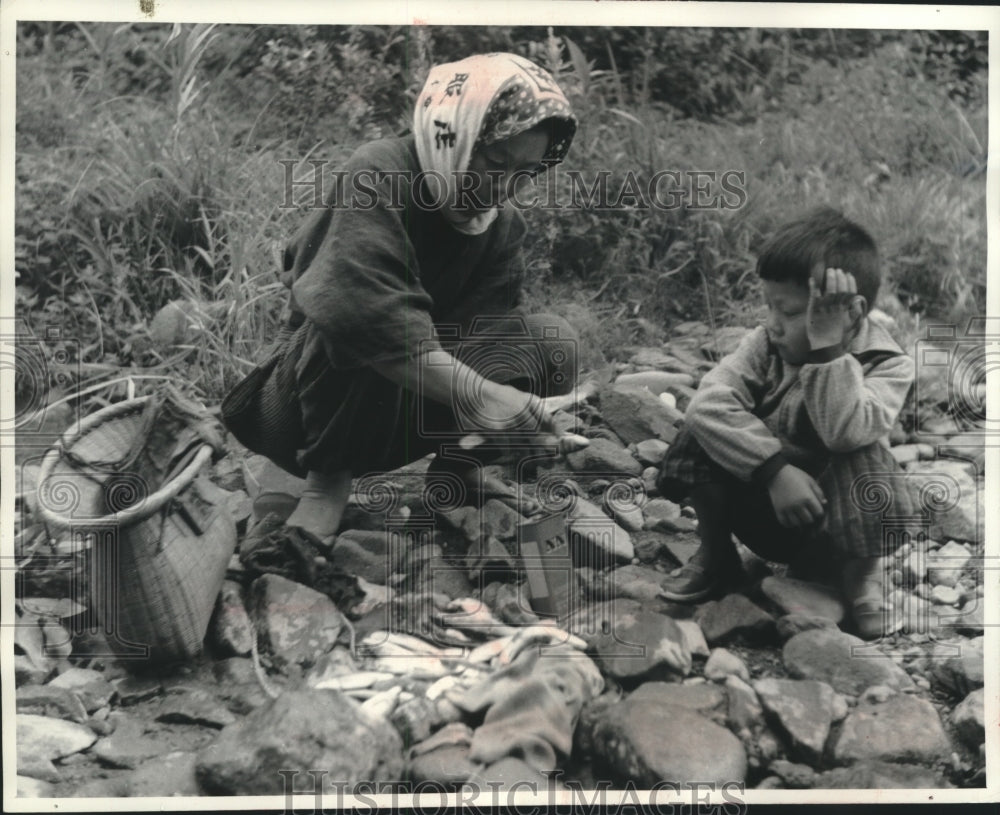 1963 Press Photo Son watches mother prepare ayu for cooking, Japan- Historic Images