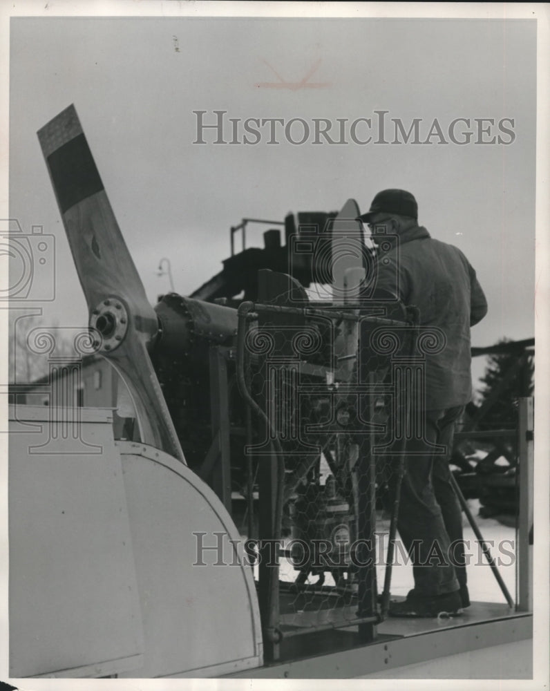 1955 Press Photo Roger Bodin tinkers with the engine of the big sled after a run