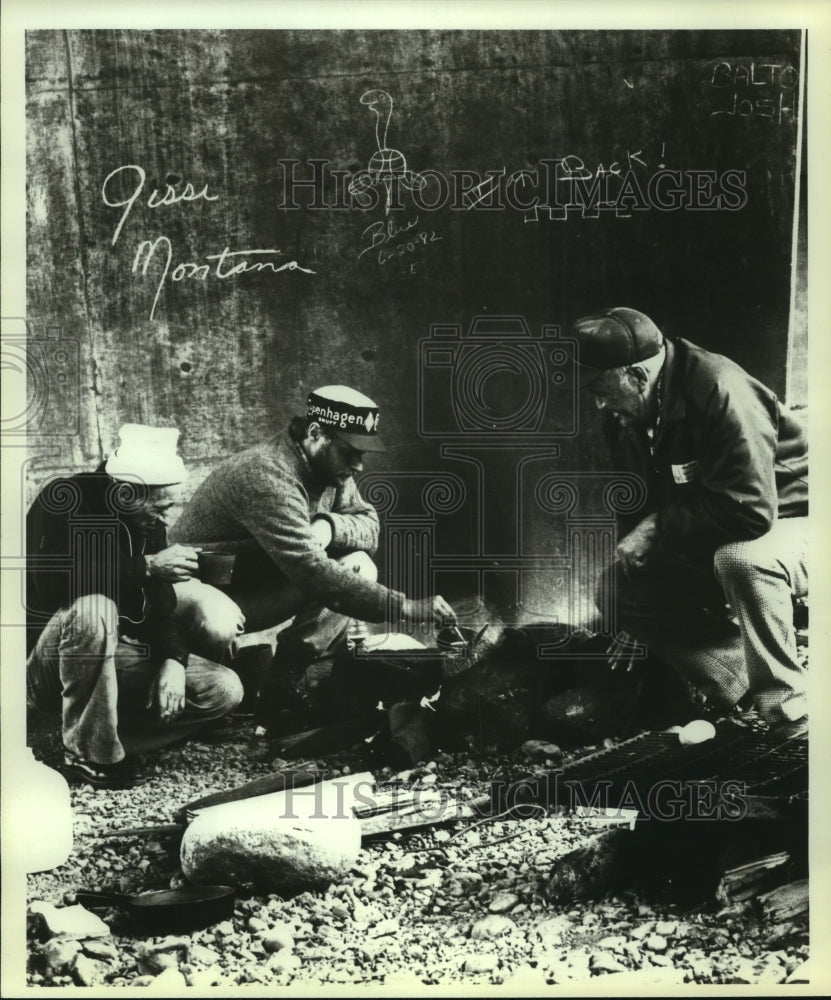 1982 Press Photo Todd Waters stirs can of beans beneath an overpass, Spokane, WA- Historic Images