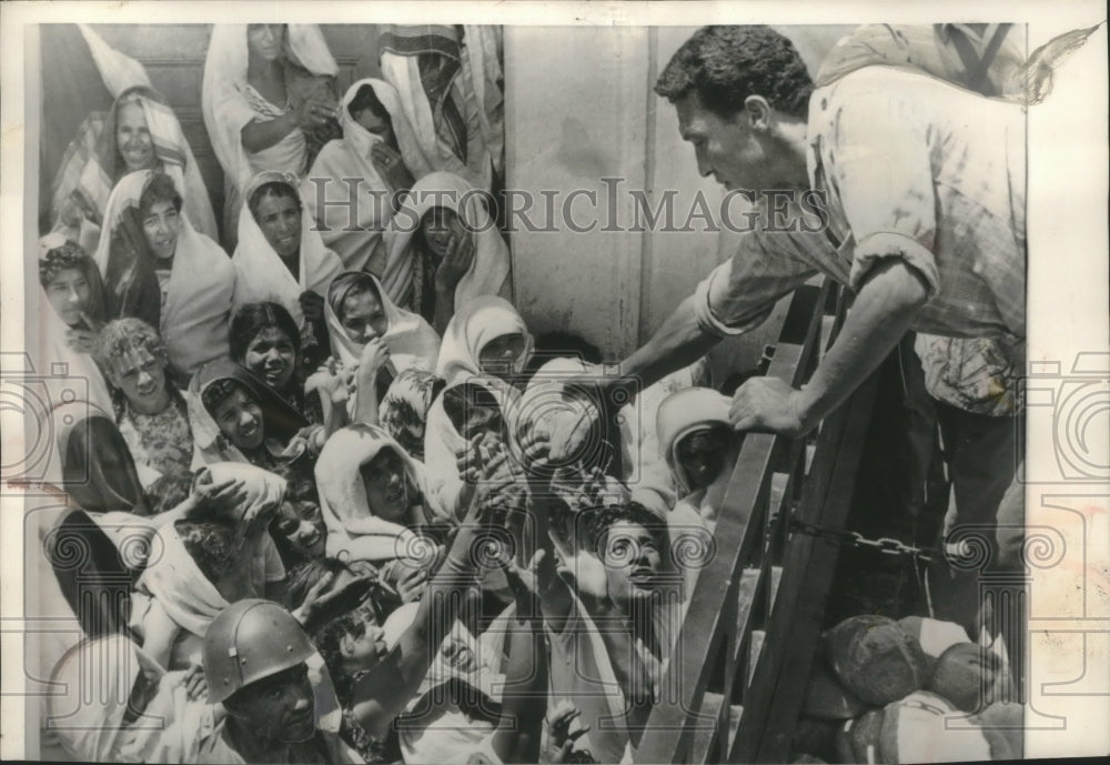 1961 Press Photo Tunisian women reach for loaves of bread from relief worker