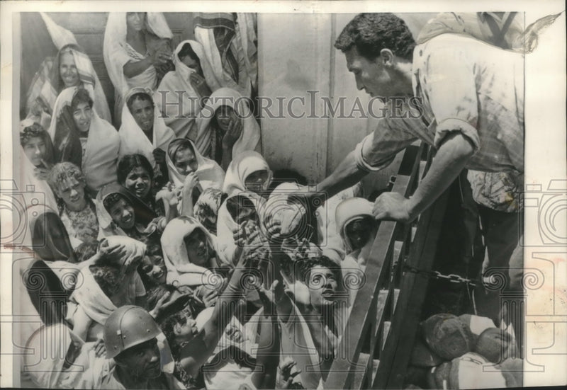 Load image into Gallery viewer, 1961 Press Photo Tunisian women reach for loaves of bread from relief worker
