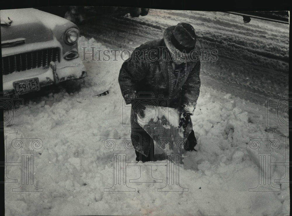 1961 Press Photo A. J. Perry shoveling snow to dig out car, Milwaukee, Wisconsin- Historic Images